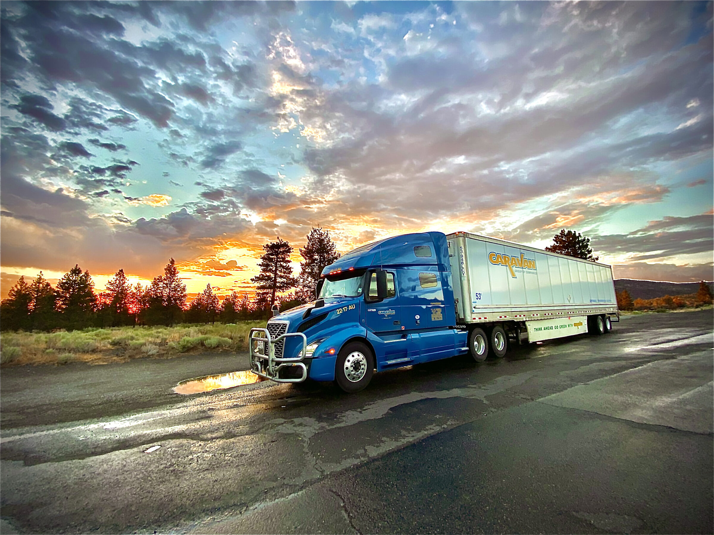 Blue Caravan tractor and reefer trailer beneath a dramatic dusk sky