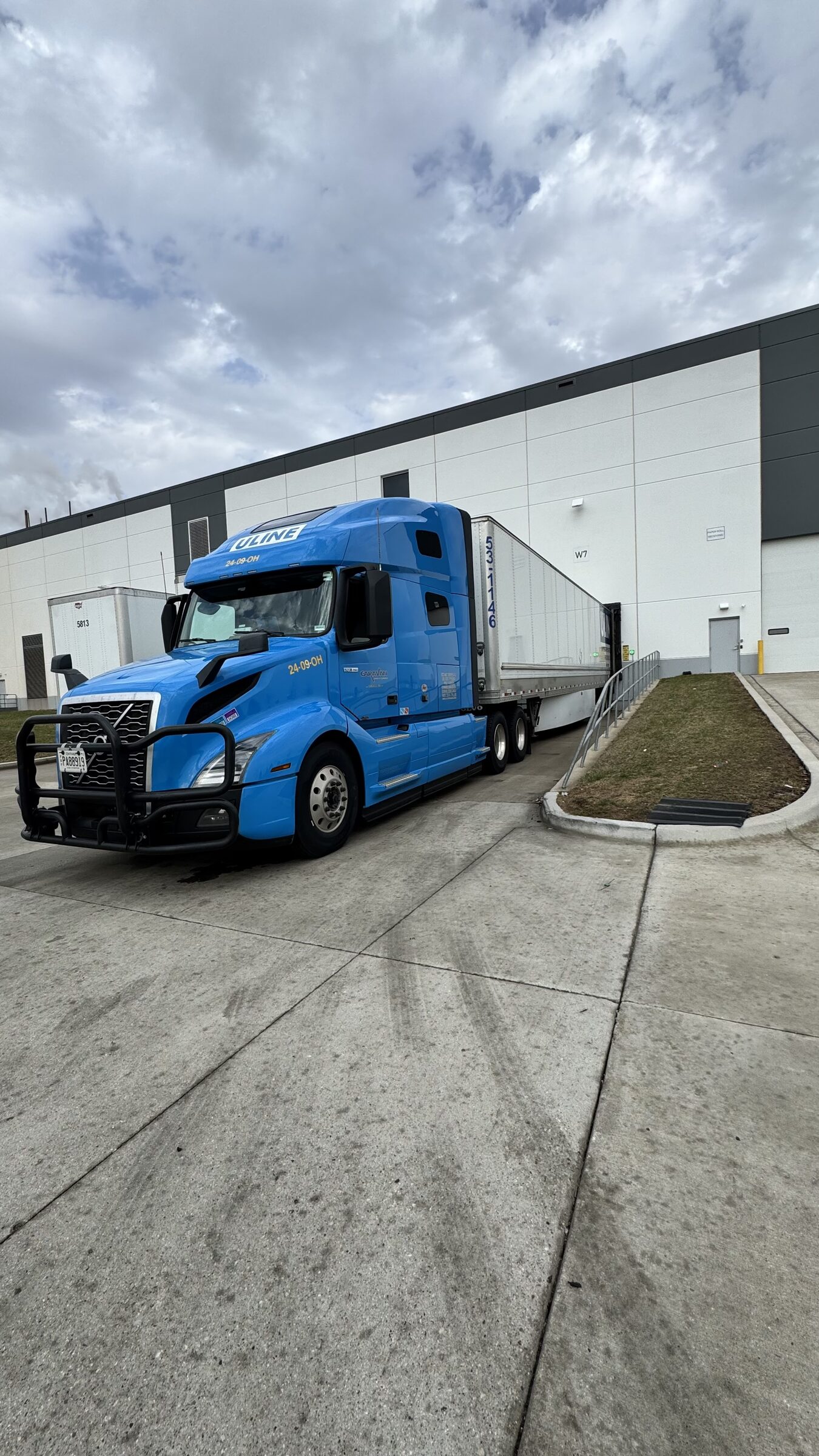 Blue Caravan tractor-trailer docked at a modern warehouse